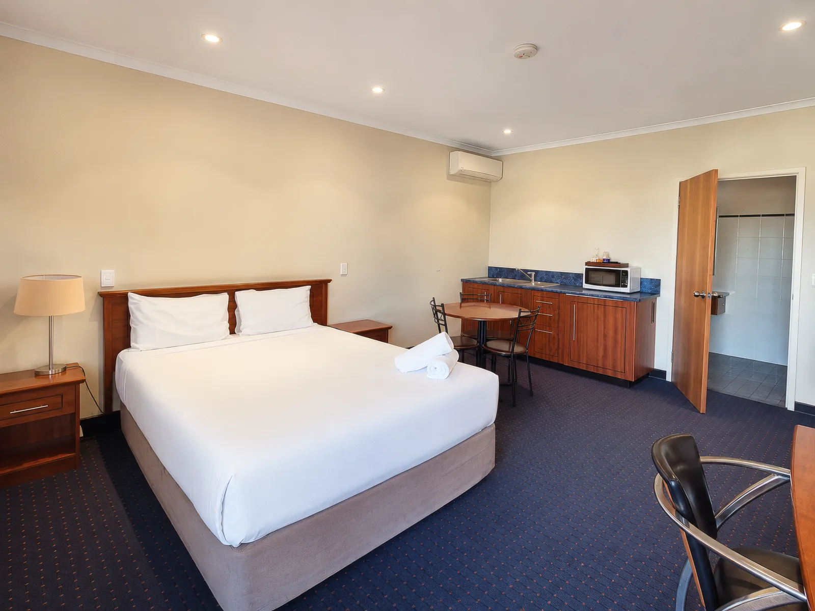 Studio Queen — queen bed, kitchenette with dining table and bathroom entrance